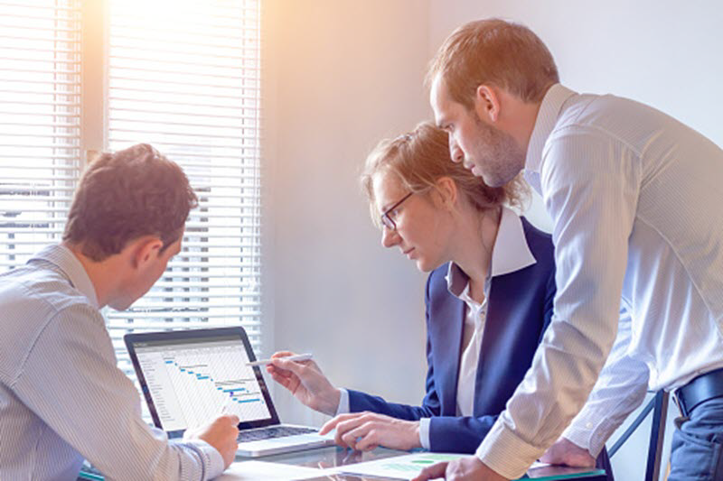 Personas en oficina viendo una tabla de Excel